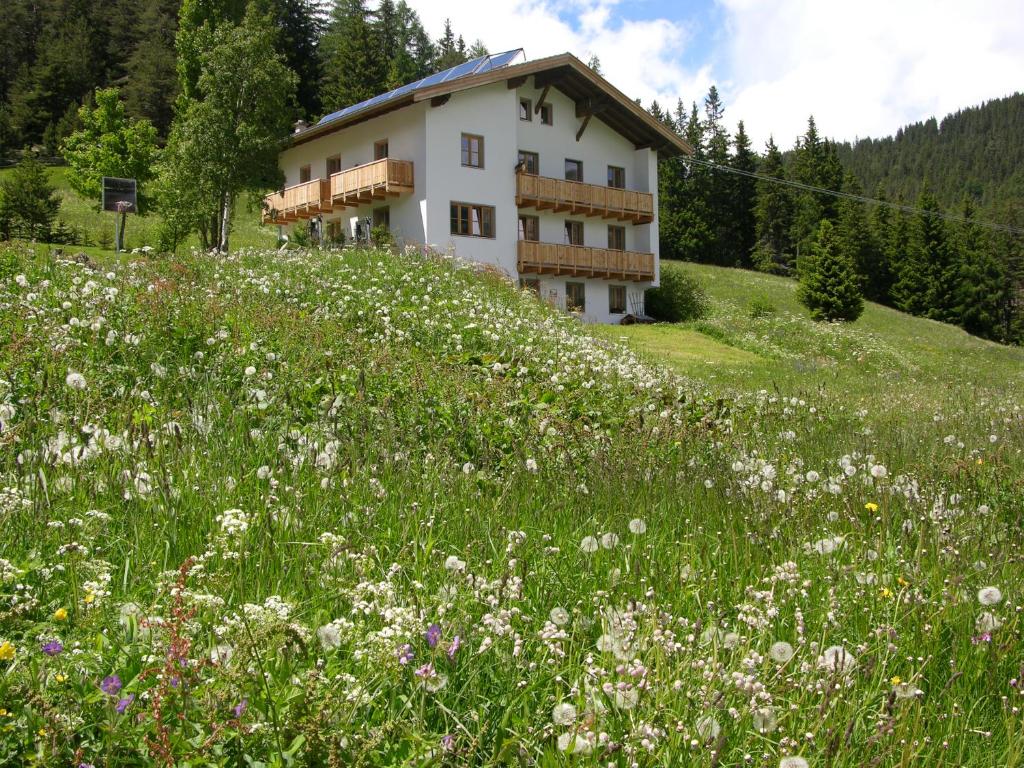 ein Gebäude auf einem Hügel mit einem Blumenfeld in der Unterkunft Tiefhof in Nauders