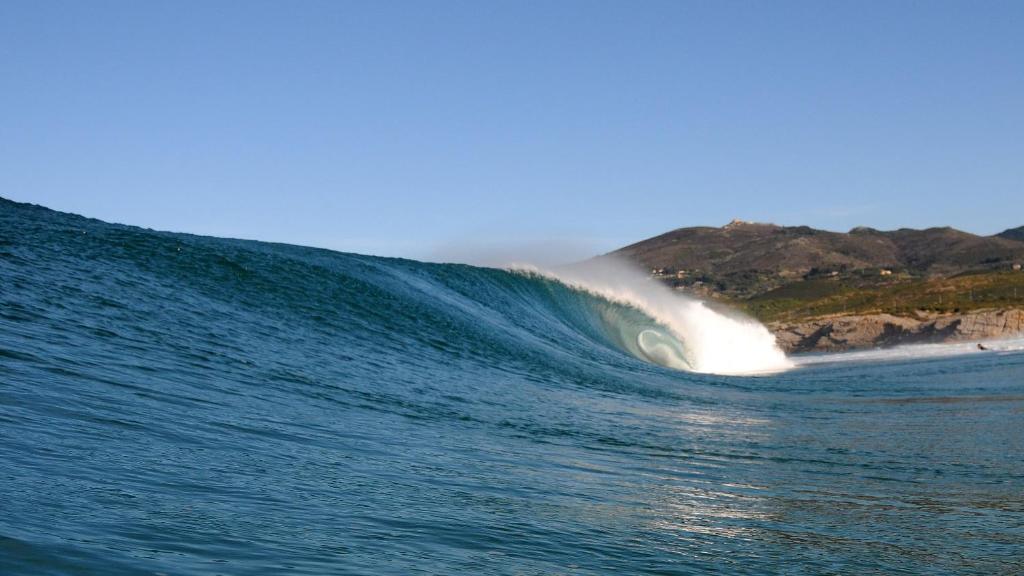 a large wave in the ocean next to a beach at Hotel Fortaleza do Guincho Relais & Châteaux in Cascais