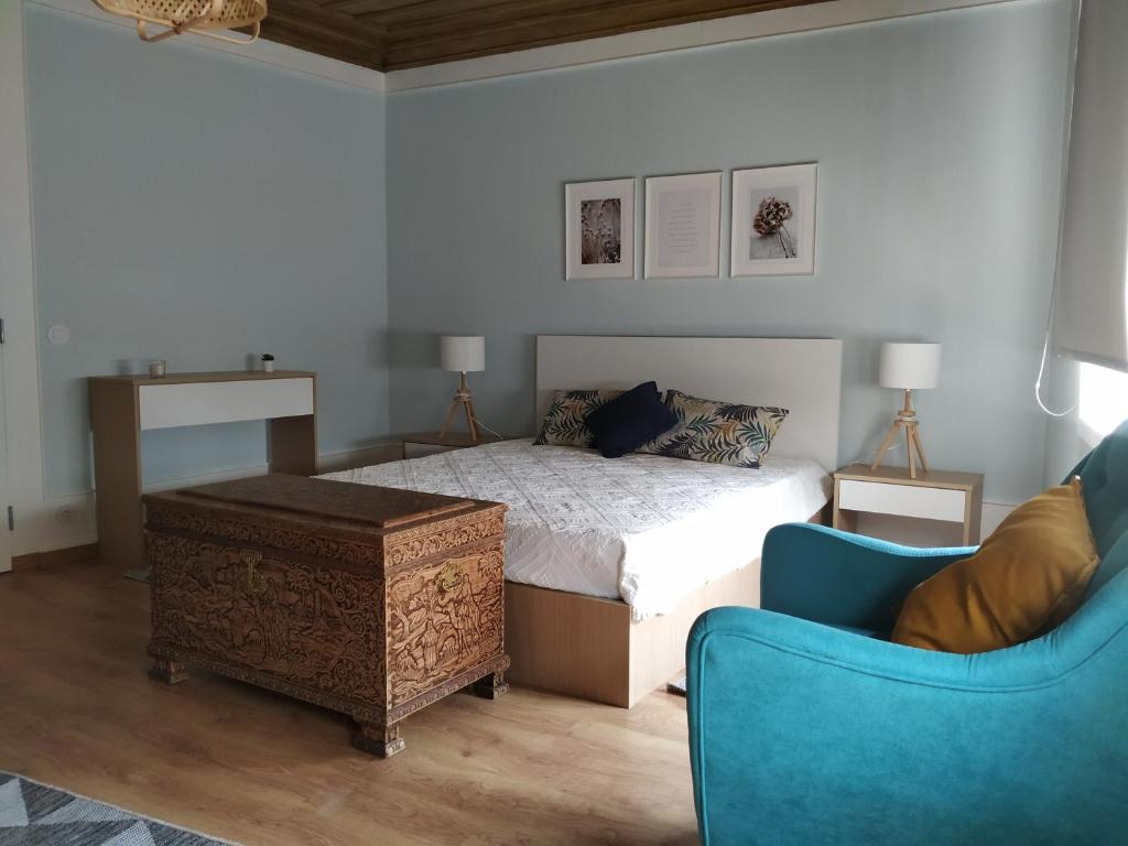 1 dormitorio con 1 cama y 1 silla azul en EntreSocalcos, en Loriga