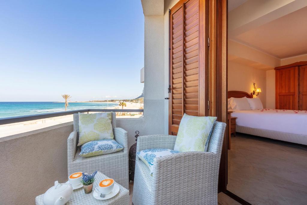 a room with a balcony with a view of the ocean at Mira Spiaggia in San Vito lo Capo