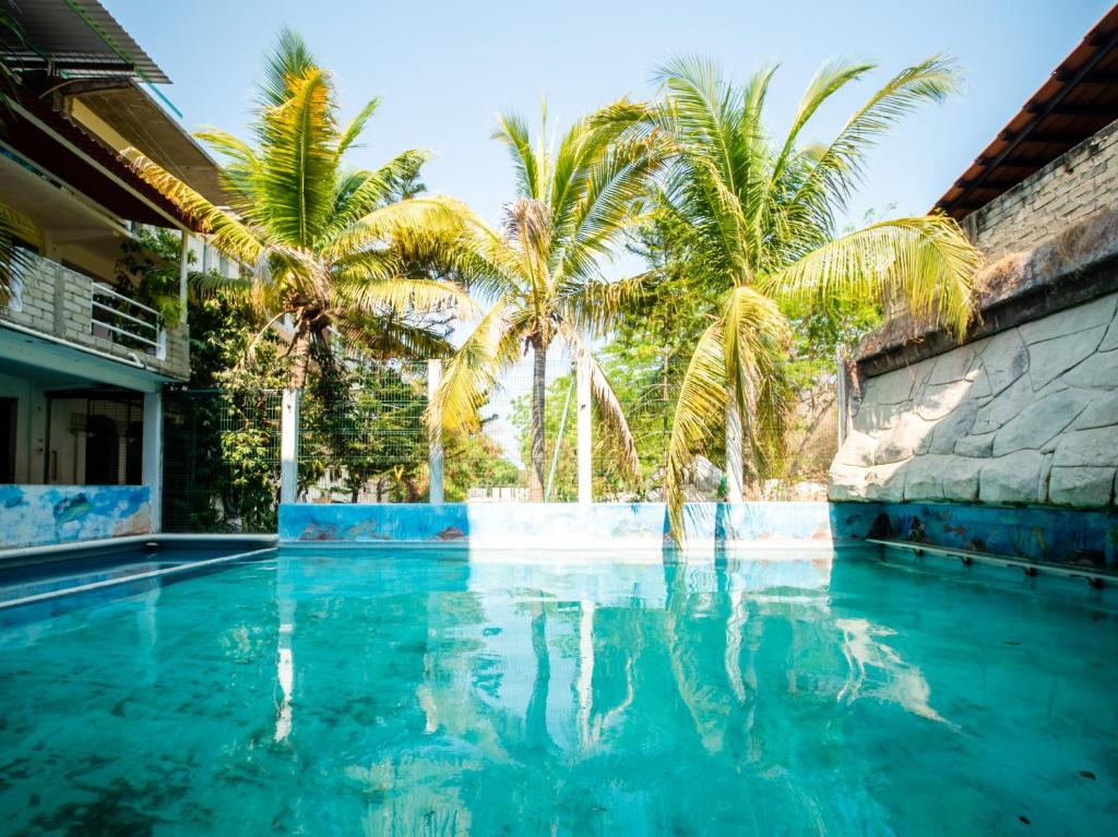 una piscina con palmeras en el fondo en OYO Hotel Betsua Vista Hermosa, Huatulco, en Santa Cruz Huatulco