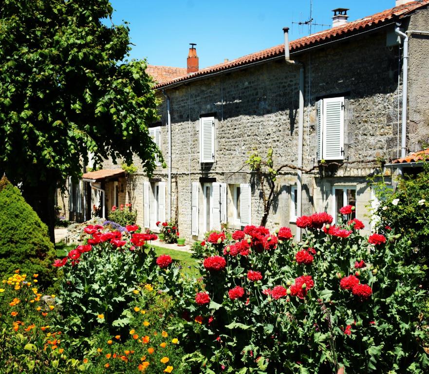 a garden of red roses in front of a stone building at Les noyers aulnay in Aulnay