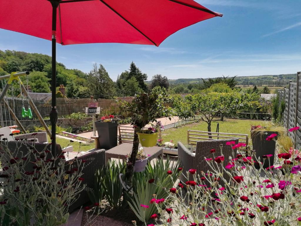 a red umbrella in a garden with flowers at Gites les petits Châteaux in Bourré