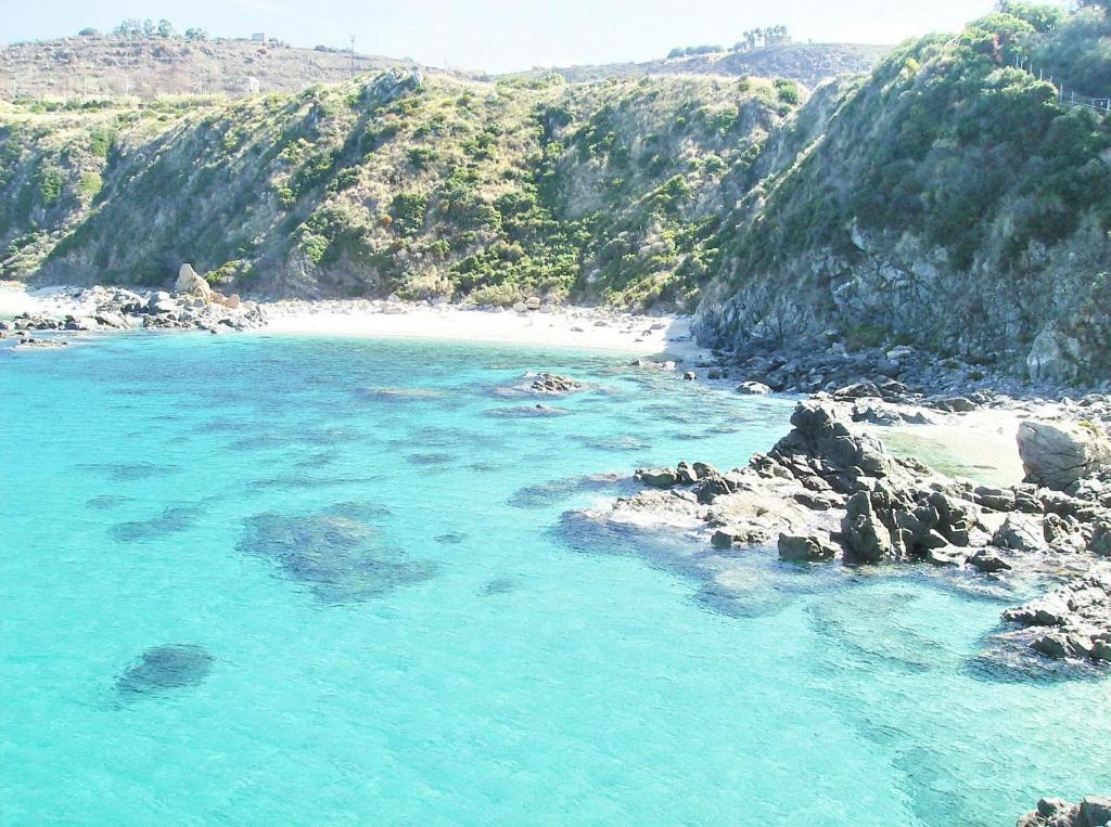 a view of a beach with blue water and rocks at Hotel Residence Riviera Calabra in Zambrone