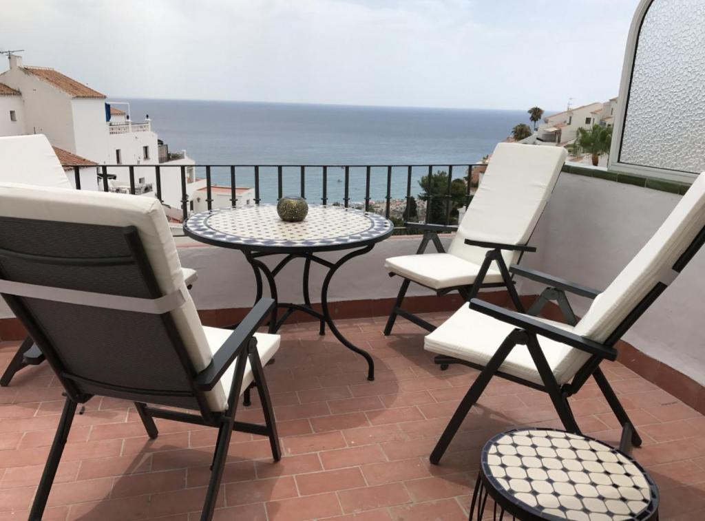 een balkon met stoelen en een tafel en uitzicht op de oceaan bij Nerja · Nerja · Beautiful seaview apartment Nerja in Nerja