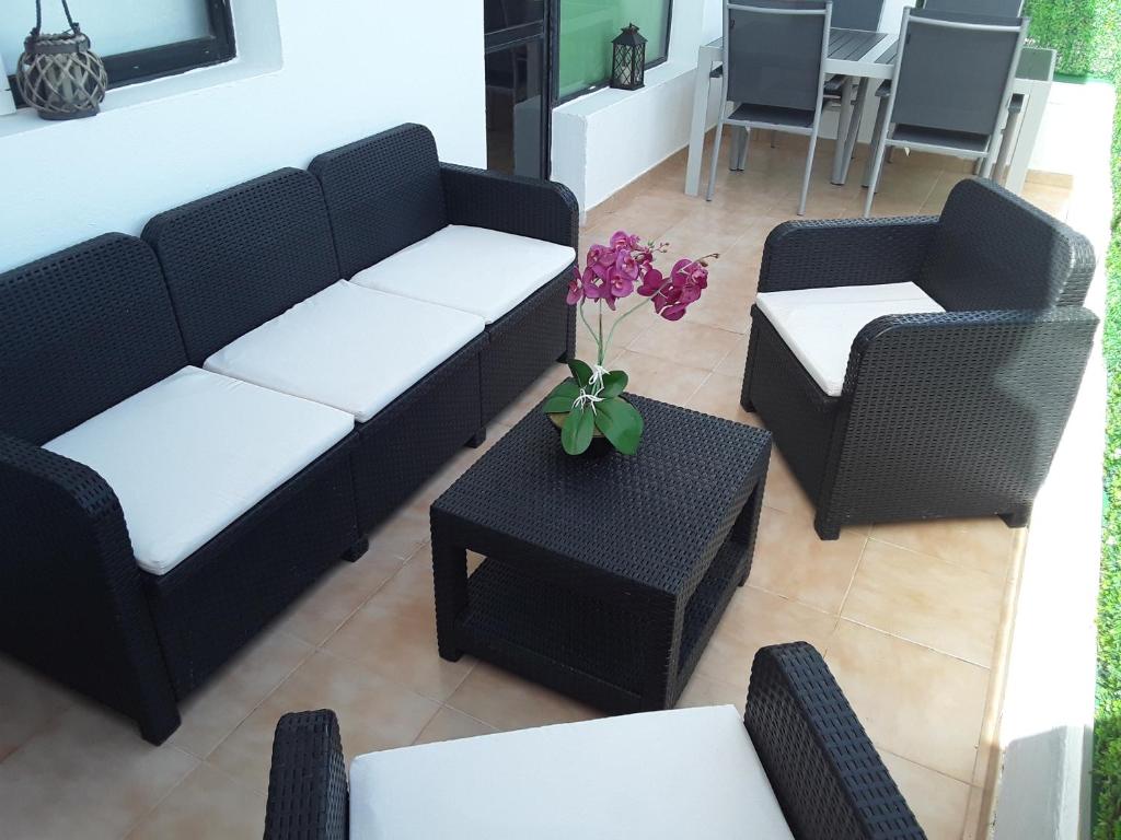 una sala de estar con 2 sofás y una mesa con flores en Guaye, en Corralejo