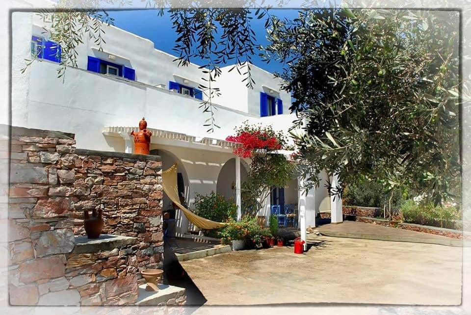 a white house with blue windows and a stone wall at Sevasti Rooms in Platis Gialos