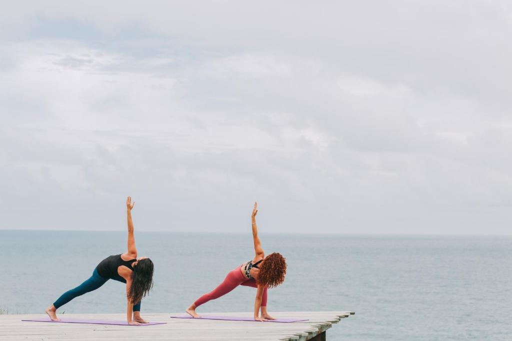 three women doing yoga on a dock near the ocean at Santa Barbara Eco-Beach Resort in Ribeira Grande