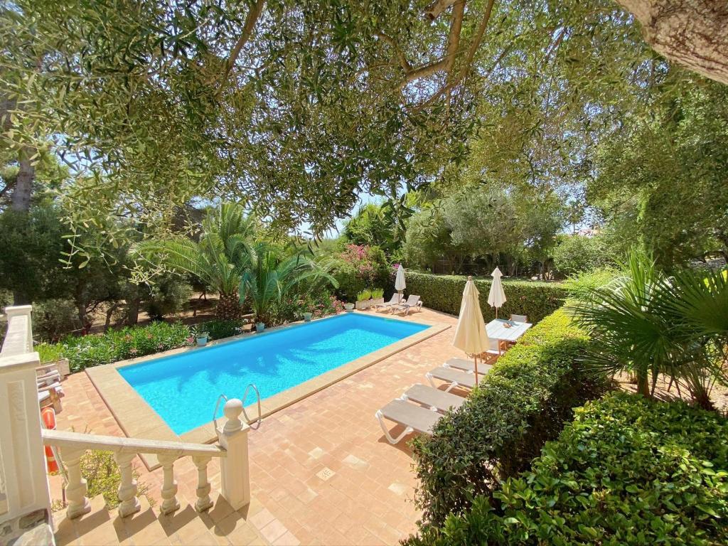 a swimming pool in a yard with chairs and trees at Boscimar in Sant Lluis