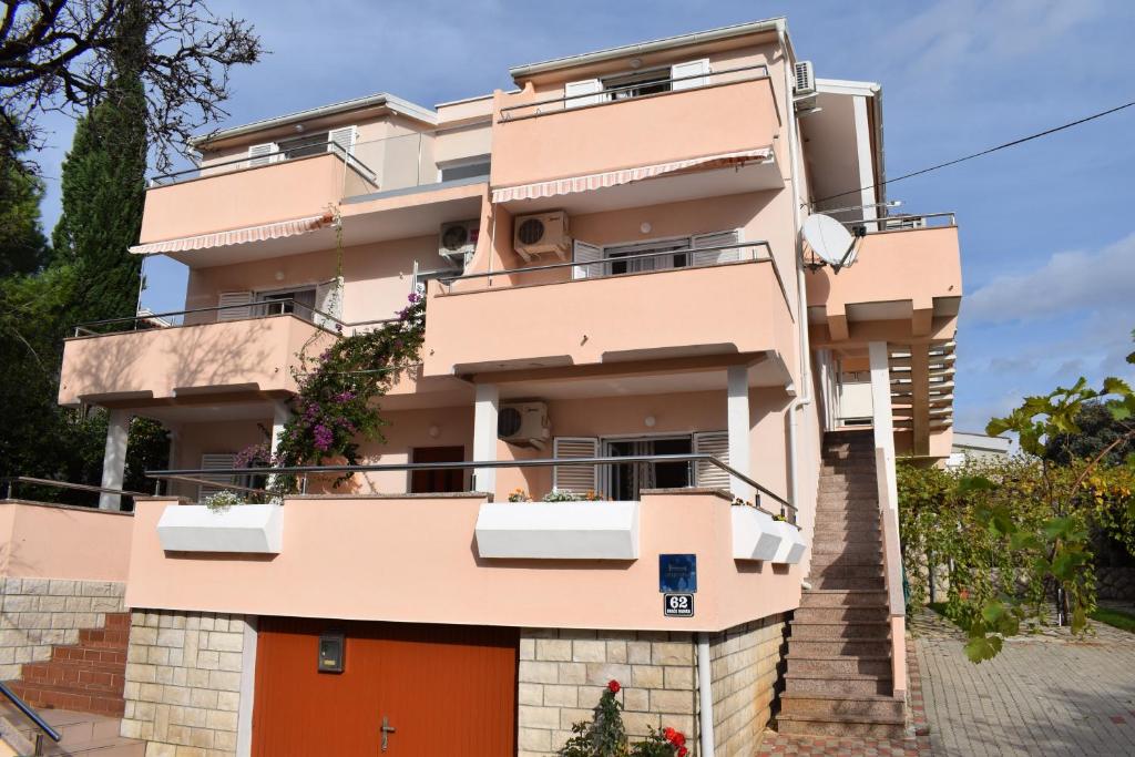 een roze gebouw met oranje deuren bij Apartmani Katica in Novalja