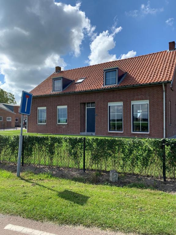 een rood bakstenen huis met een blauw bord ervoor bij familieverblijf De groene Specht in Sluis