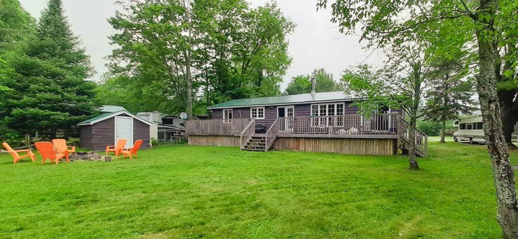 a house with a deck and chairs in a yard at Beautiful 3 Bdrm + Bunkie Waterfront Cottage Near Gull Lake in Minden