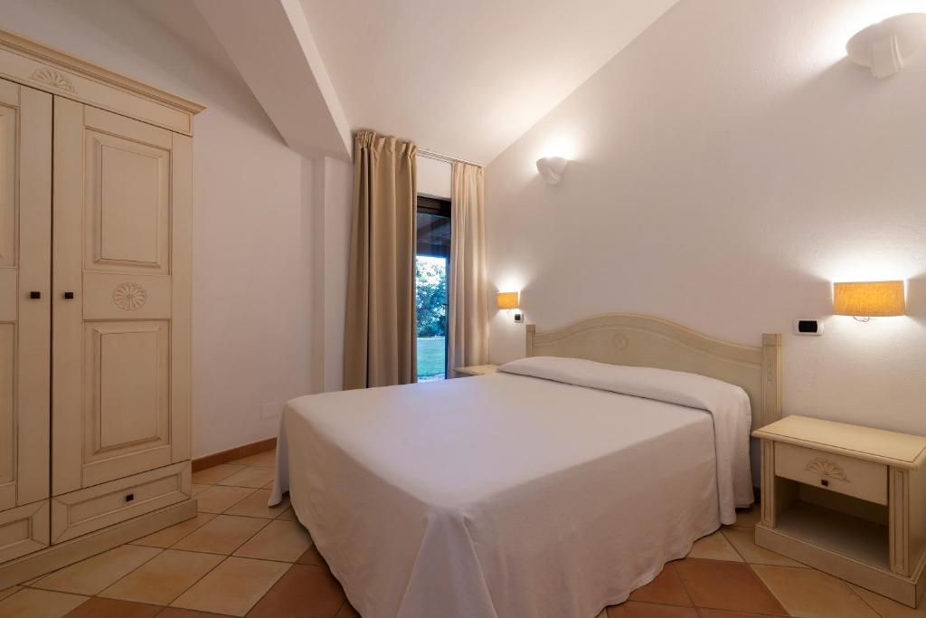 a bedroom with a white bed and a window at Porto Giunco Residence in Villasimius