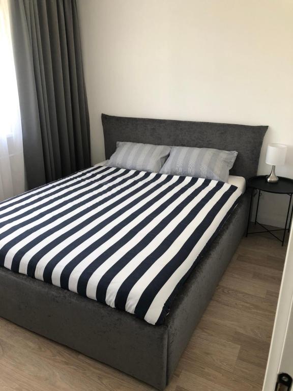 a bed with a black and white striped mattress at Good Night apartaments in Panevėžys