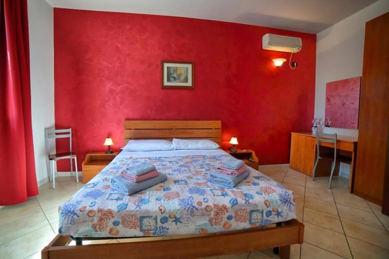 1 dormitorio con 1 cama con pared roja en Maxpensione, en Morciano di Leuca