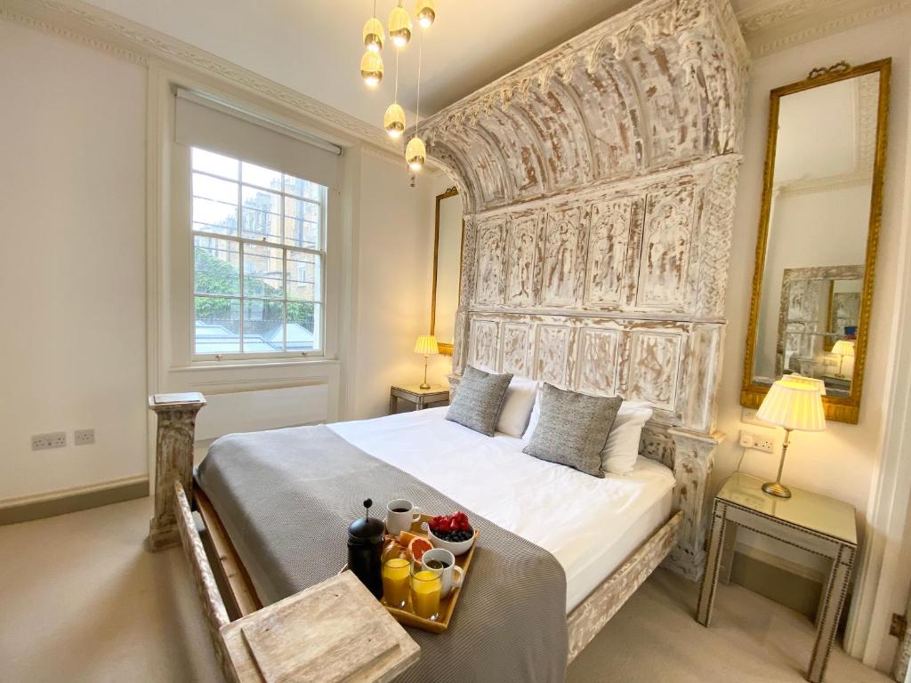 una camera da letto con un grande letto con una grande testiera di Stylish Apartments in Pimlico & Westminster a Londra
