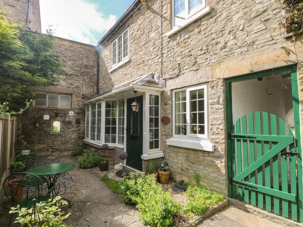a brick house with a green door and a table at Wedgewood Cottage in Leyburn