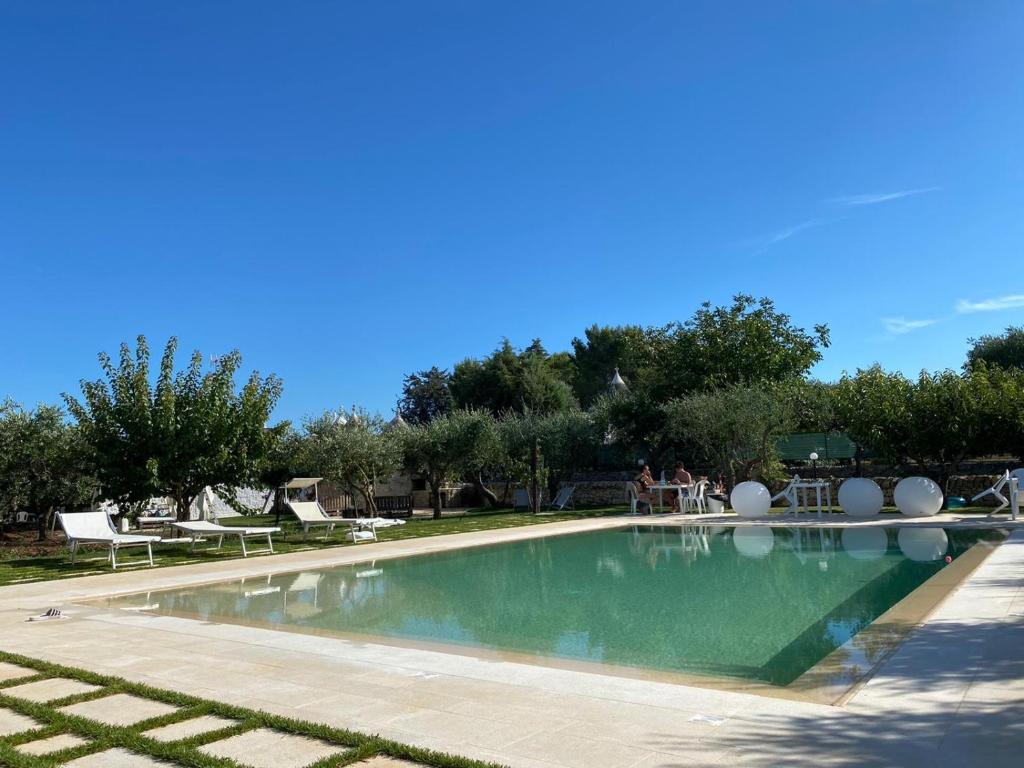 a swimming pool in a park with people sitting around it at Aria di Casa Country Resort in Alberobello