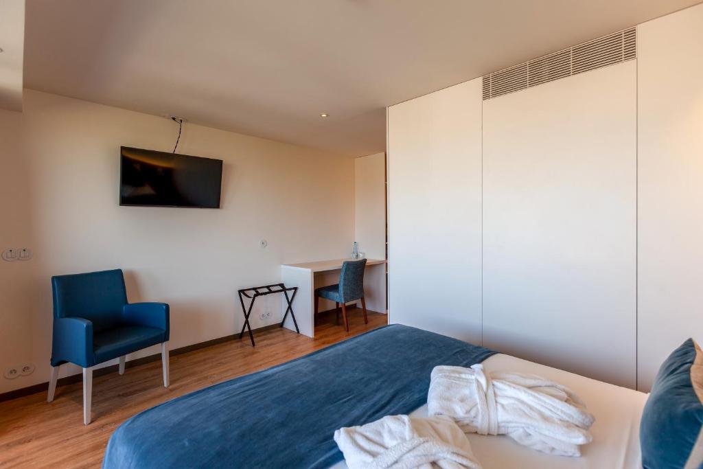 a bedroom with a bed and a blue chair at Sea Porto Hotel in Matosinhos