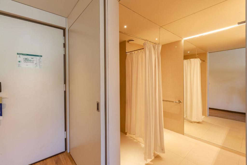 a bathroom with a glass door and a mirror at Sea Porto Hotel in Matosinhos