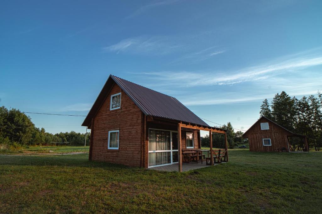 una casa con techo de gambrel en un campo de hierba en Vėjo Malūnų sodyba en Paserninkai