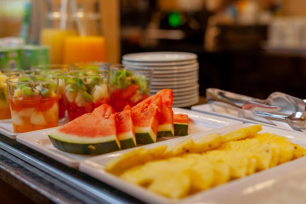 a buffet with a tray of food with watermelon and fruit at Sea Porto Hotel in Matosinhos