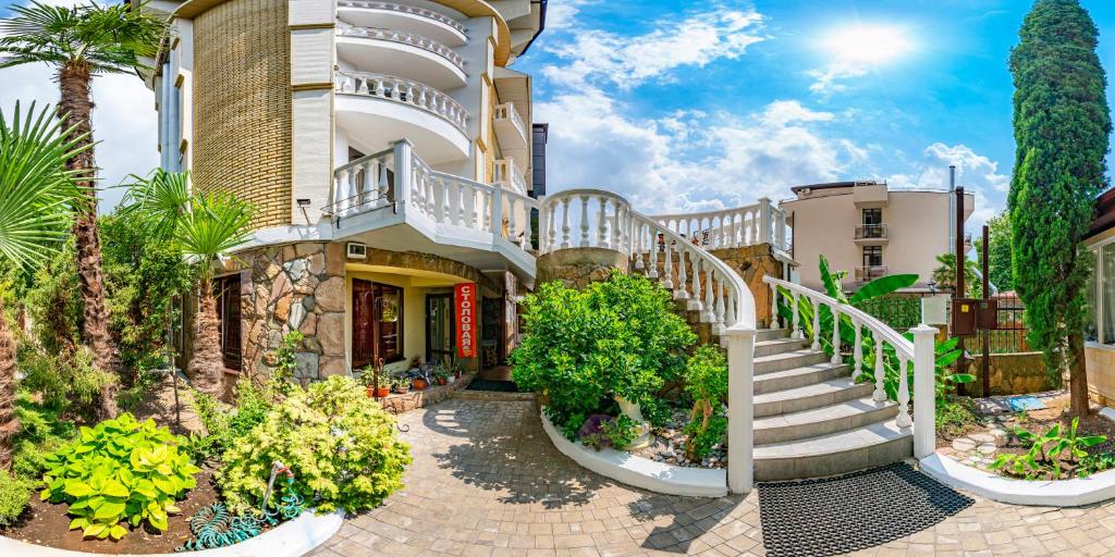 un edificio con escaleras y plantas delante de él en Rostovchanka resort inn, en Lazarevskoye