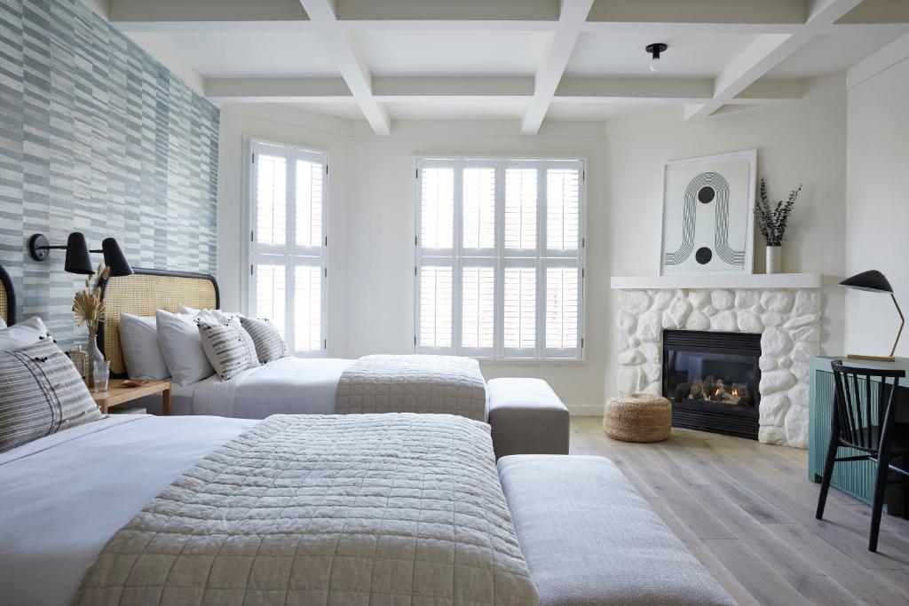 a bedroom with two beds and a fireplace at San Luis Creek Lodge in San Luis Obispo