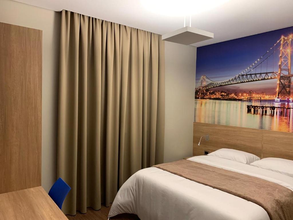 a bedroom with a bed with a painting of a bridge at Hotelog in Campina Grande do Sul