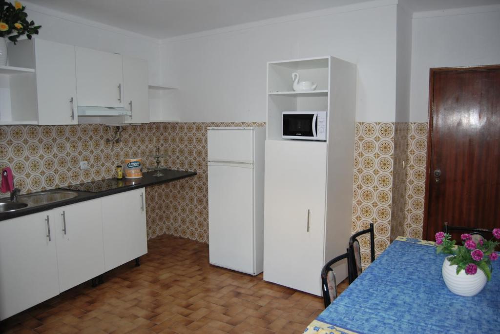 uma cozinha com um frigorífico e uma mesa com uma mesa azul em Apartamentos Mota na Nazaré