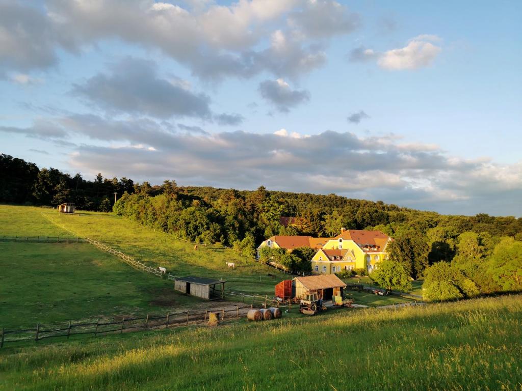 a farm with a house and a field with trees at Cseri Kastélyszálló in Tótvázsony