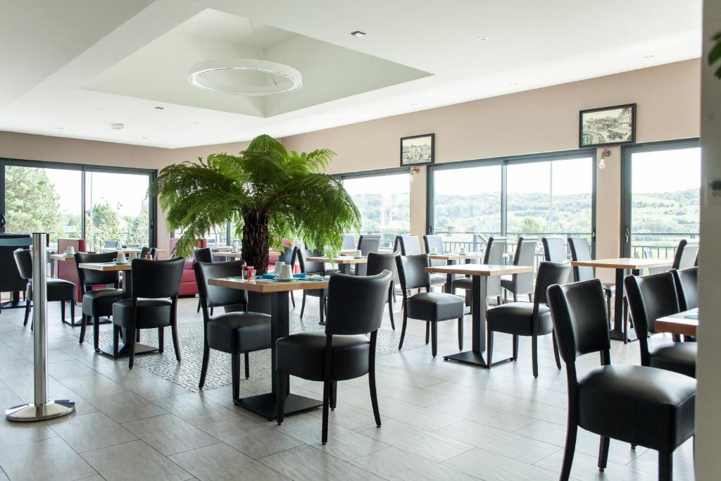 a restaurant with tables and chairs and windows at Hotel Les Galets in Criel-sur-Mer