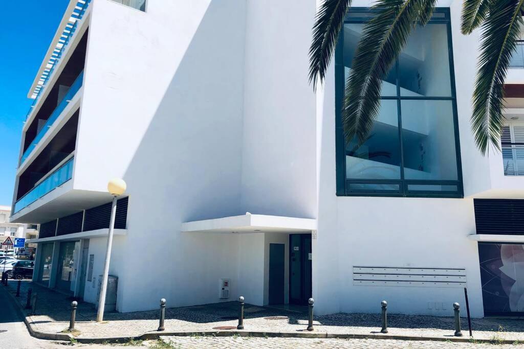 a white building with a palm tree in front of it at Vacations home Albufeira in Albufeira