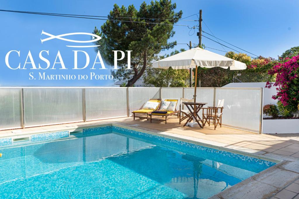 a swimming pool with a table and an umbrella at Casa da Pi in São Martinho do Porto