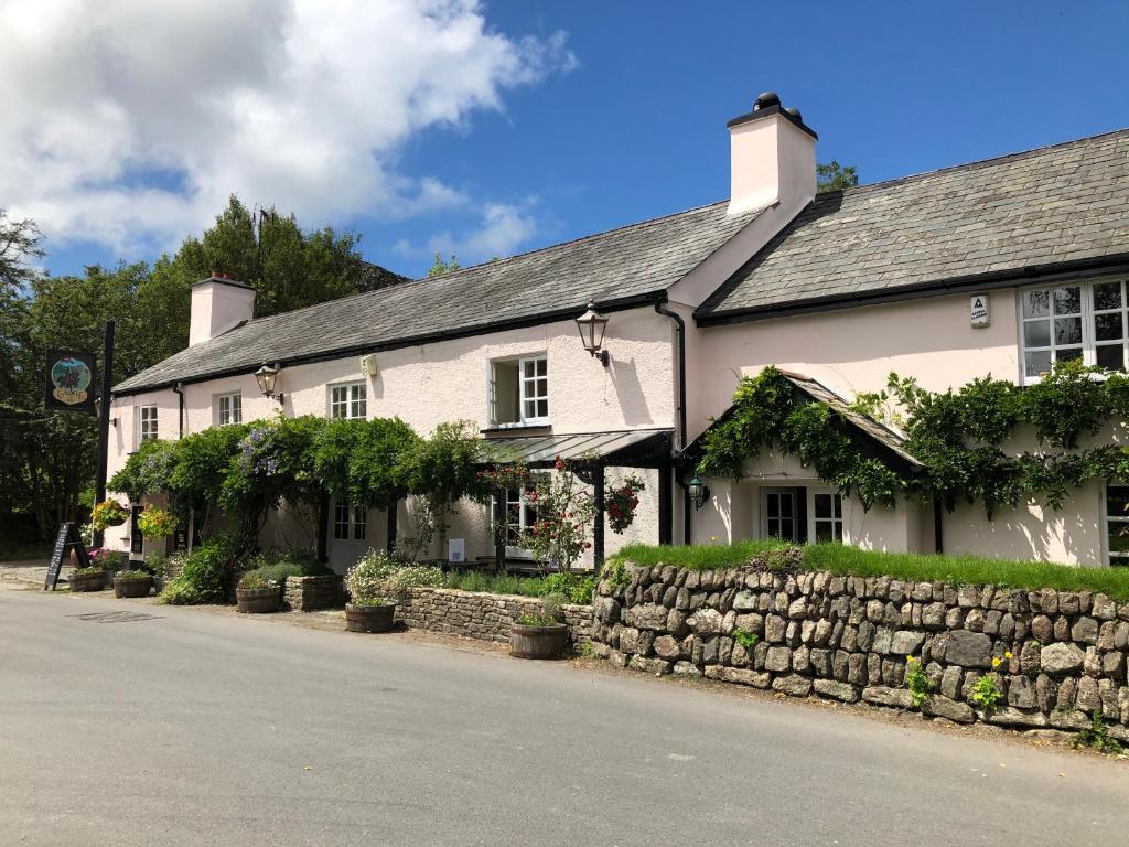 una casa blanca con una pared de piedra junto a una calle en Castle Inn, en Lydford