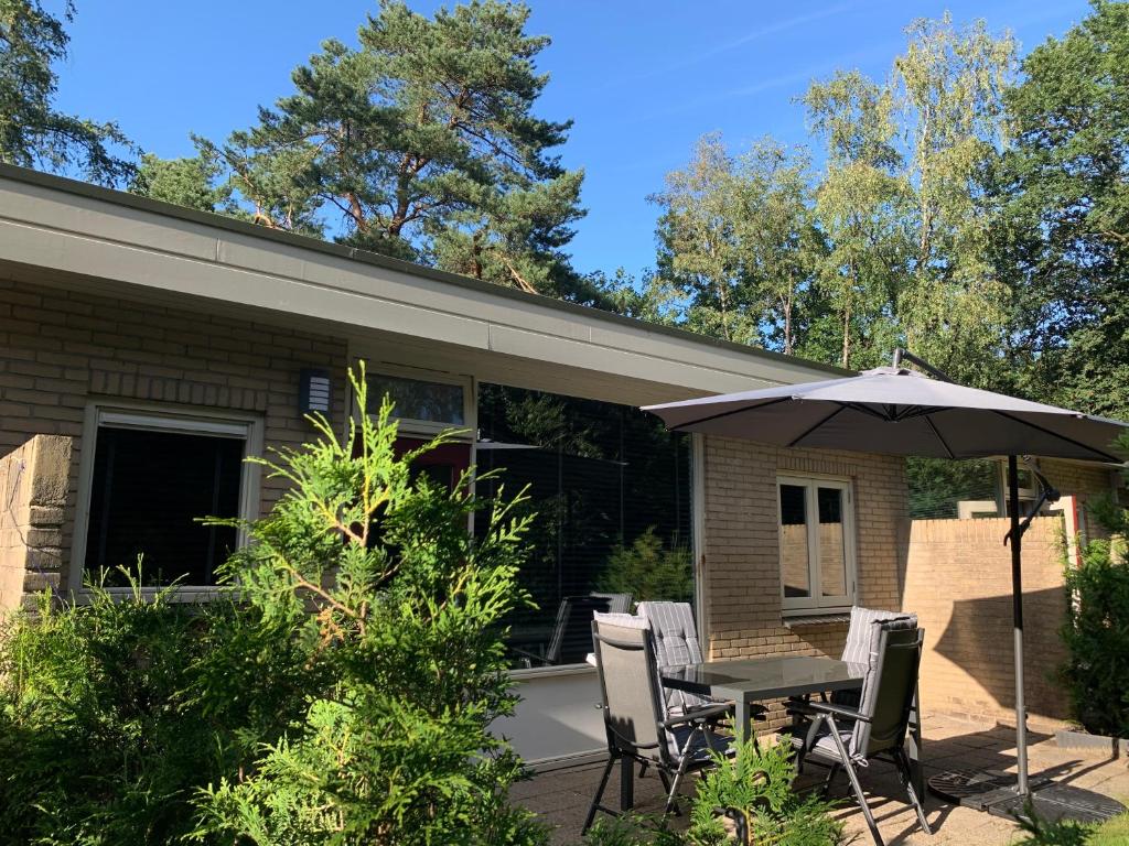 a patio with an umbrella and a table and chairs at Bonte Specht: tot rust komen in de natuur! in Otterlo