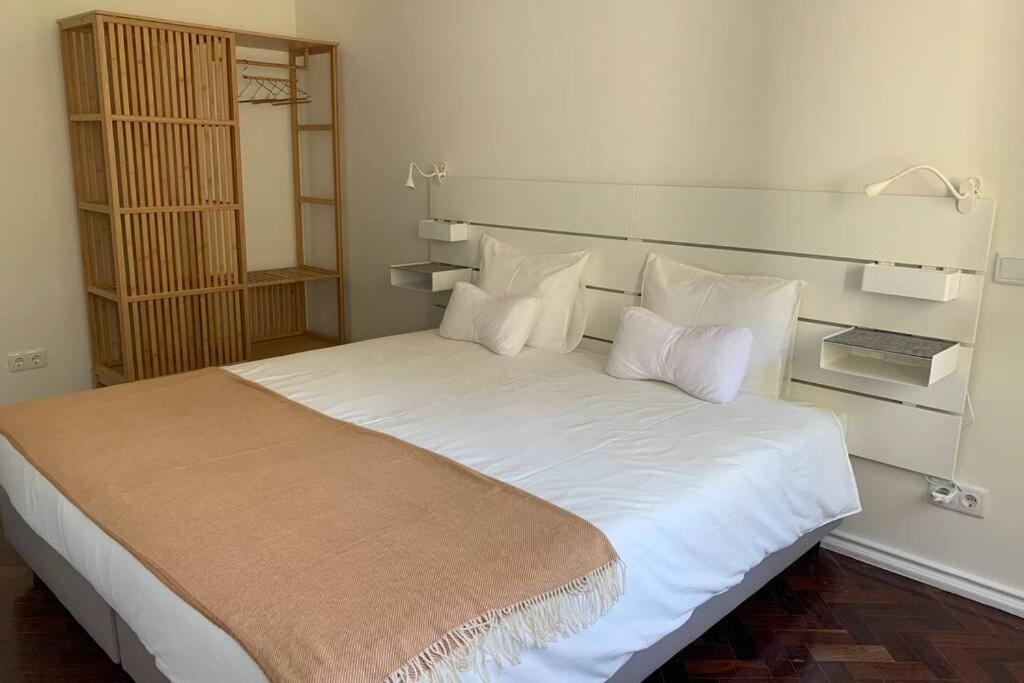 een slaapkamer met een groot bed met witte lakens en kussens bij Casa do Largo Sardinha - Very central apartment in Lissabon