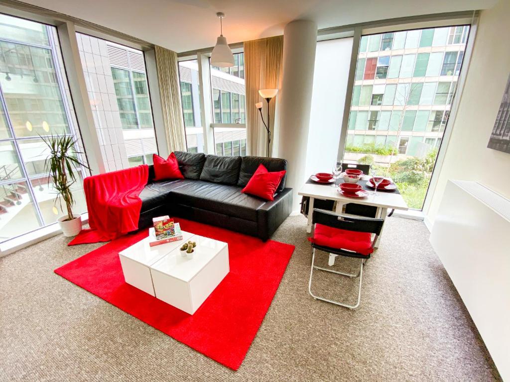 ein Wohnzimmer mit einem schwarzen Sofa und roten Kissen in der Unterkunft City Centre Apartment - Free Parking, Fast Wifi, Smart TV with Netflix and Xbox by Yoko Property in Milton Keynes