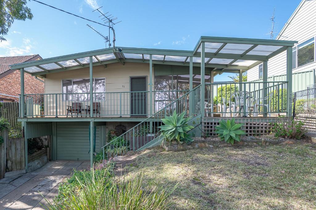 a house with a deck with a patio at Batehaven Beach House in Batehaven