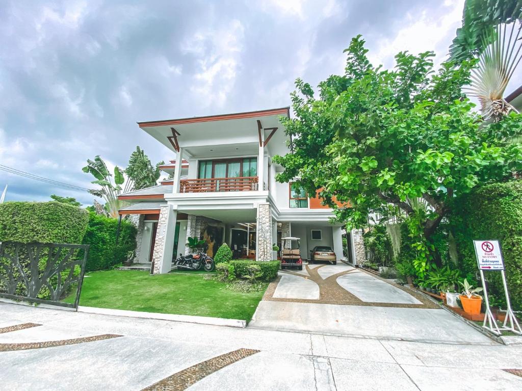 una gran casa blanca con un árbol delante en Royal Sammuk Villa, en Bang Saen