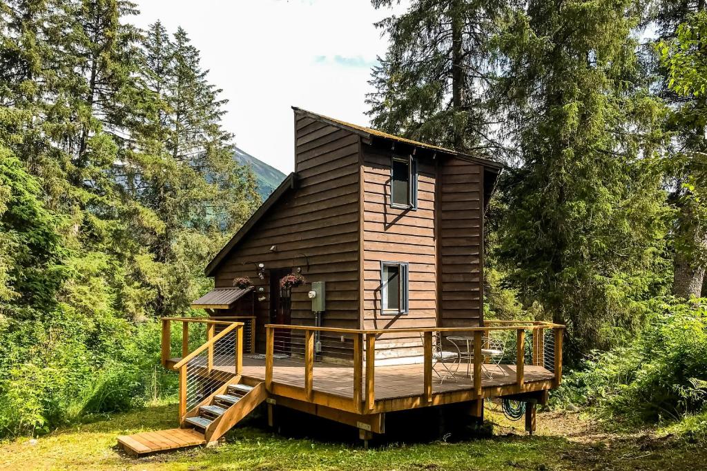 eine Hütte im Wald mit einer großen Terrasse in der Unterkunft Girdwood Mountain House in Girdwood