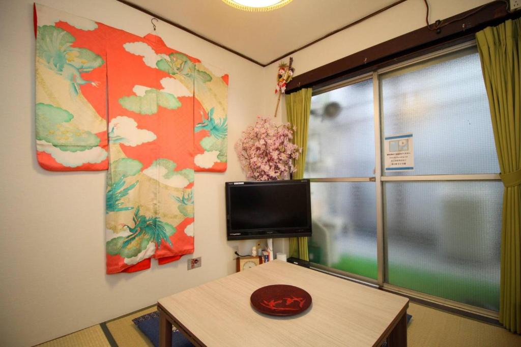 Habitación con mesa, TV y ventana. en Daiichi ichiba Building, en Tokio