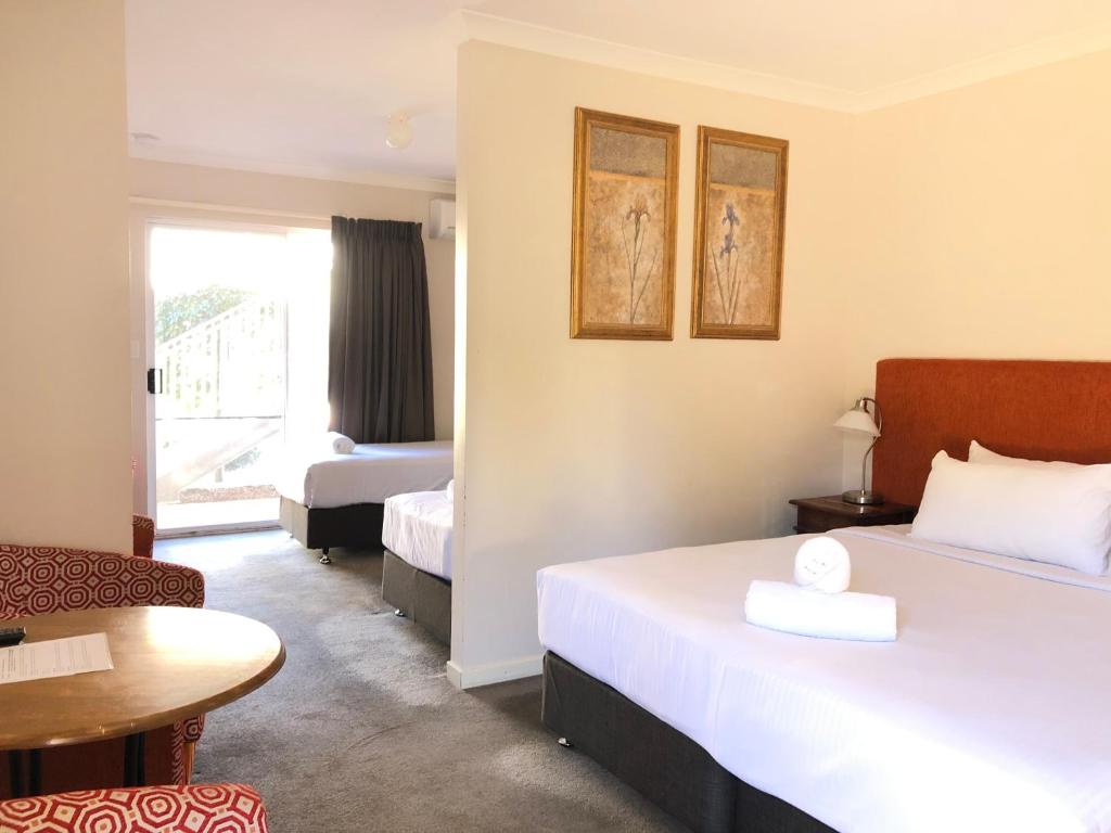 um quarto de hotel com duas camas e uma mesa em Higgins Lane Motel em Margaret River