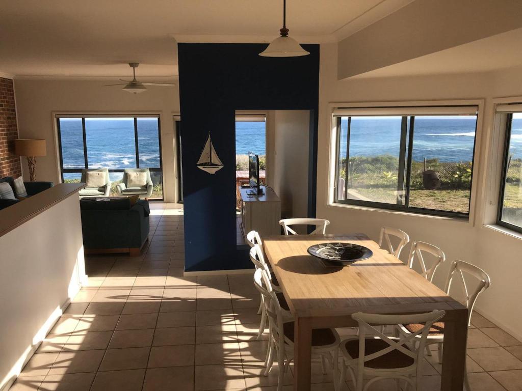 a dining room with a table and chairs and the ocean at Ocean Views air conditioned luxury with beautiful ocean views in Anna Bay