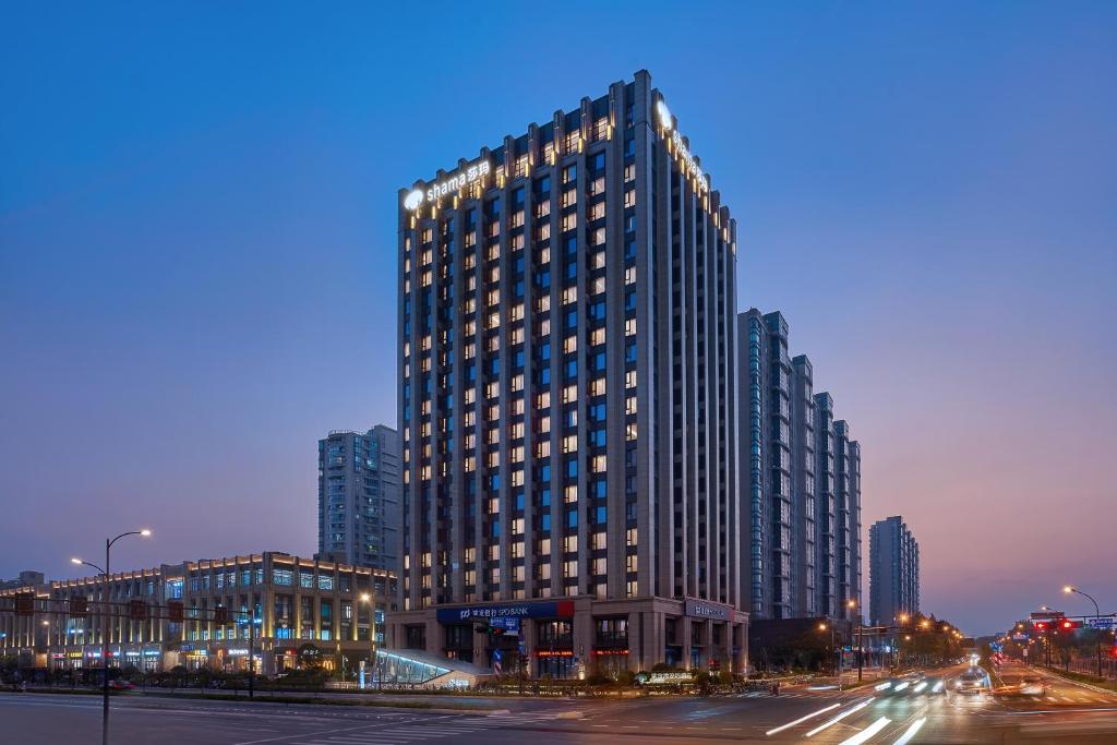 Shama Serviced Apartments Zijingang Hangzhou - Zijingang Campus Zhejiang University, Subway Line2&5 Sanba Station في هانغتشو: مبنى طويل وبه العديد من النوافذ على شارع المدينة