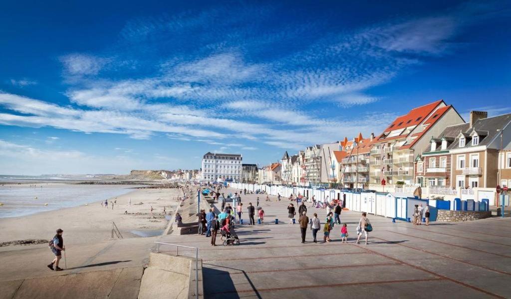 a group of people walking on a beach with buildings at La Tanatte de wimereux sur la côte d opale in Wimereux