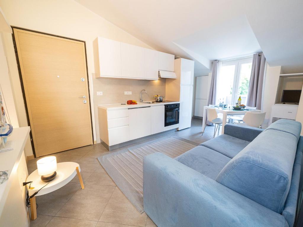un salon avec un canapé bleu et une cuisine dans l'établissement Parco del Mare - Relax near the sea and city centre, à Borghetto Santo Spirito