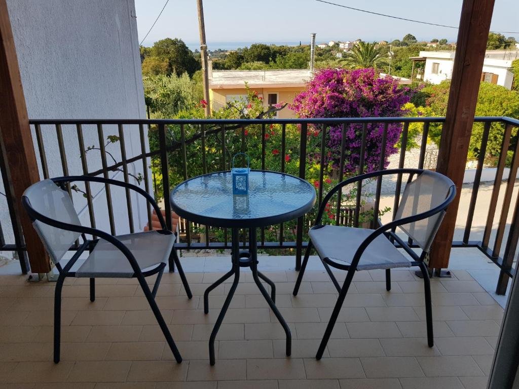 een glazen tafel en 2 stoelen op een balkon bij Filippos Apartments "Apartment 2" in Spartia