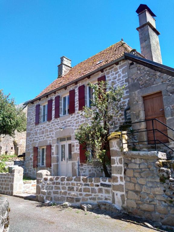 an old stone house with red shutters on it at Maison Village Hautefage avec piscine chauffée in Hautefage