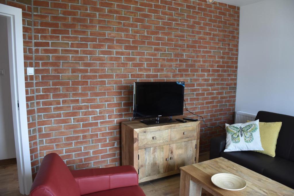 a living room with a tv on a brick wall at Klara - Harmonia Oliwska in Gdańsk
